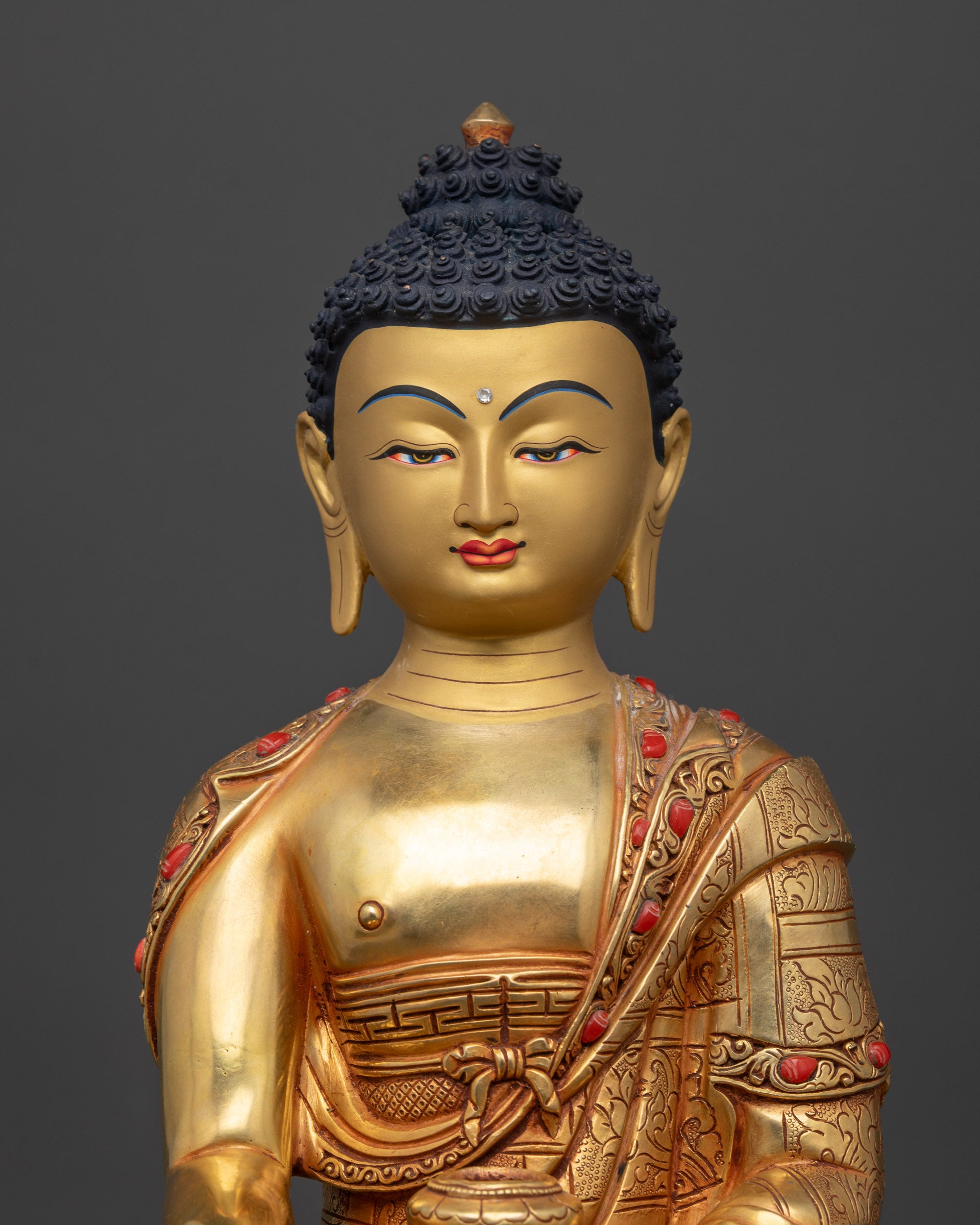 Regular close up of Shakyamuni Buddha sculpture in coral-inlay monk’s robe
