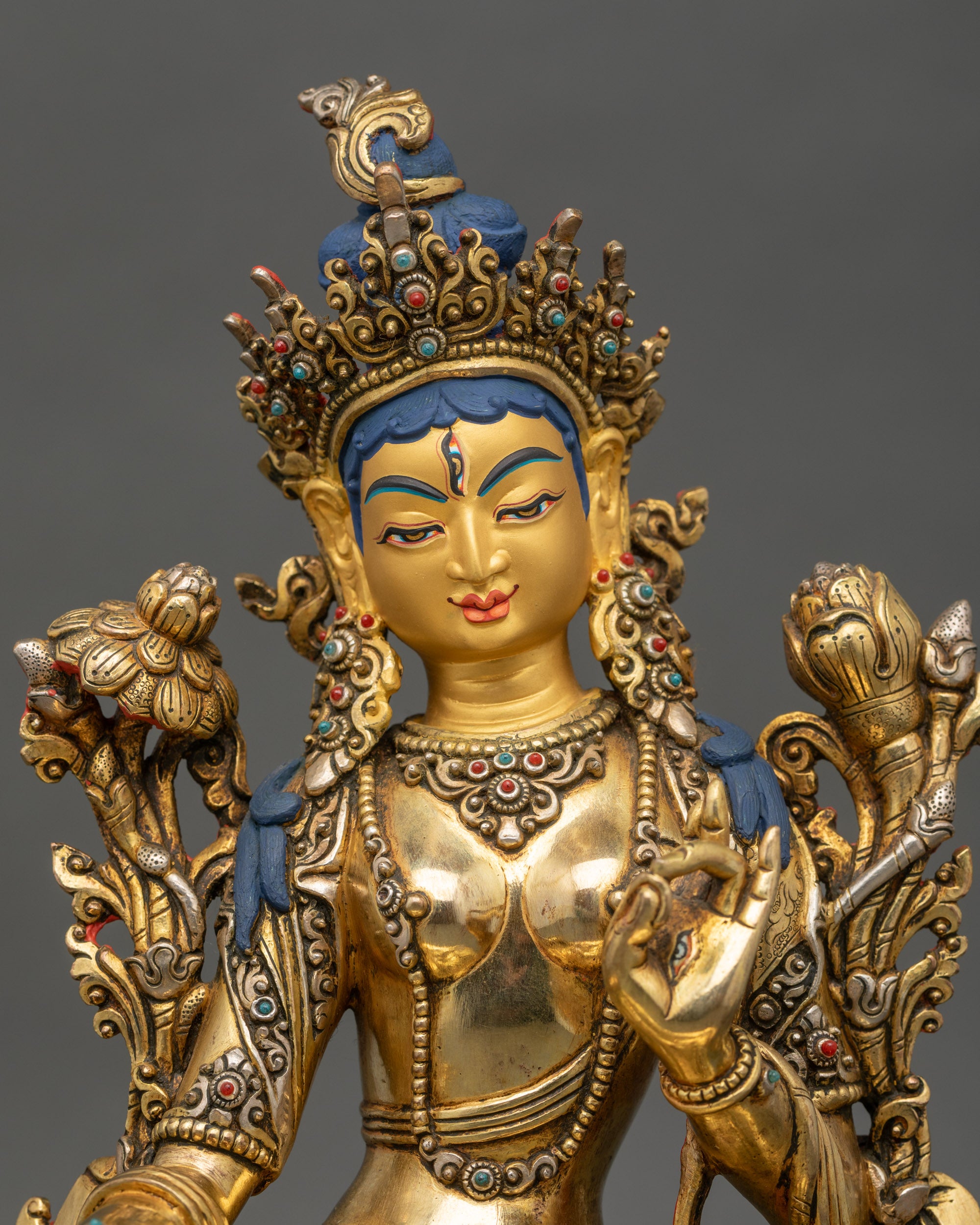 Regular close up of White Tara Statue showing serene gold-gilded face and lotus base