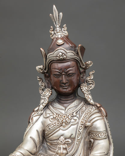 Regular close up of oxidized Guru Rinpoche statue showing silver robes and lotus hat