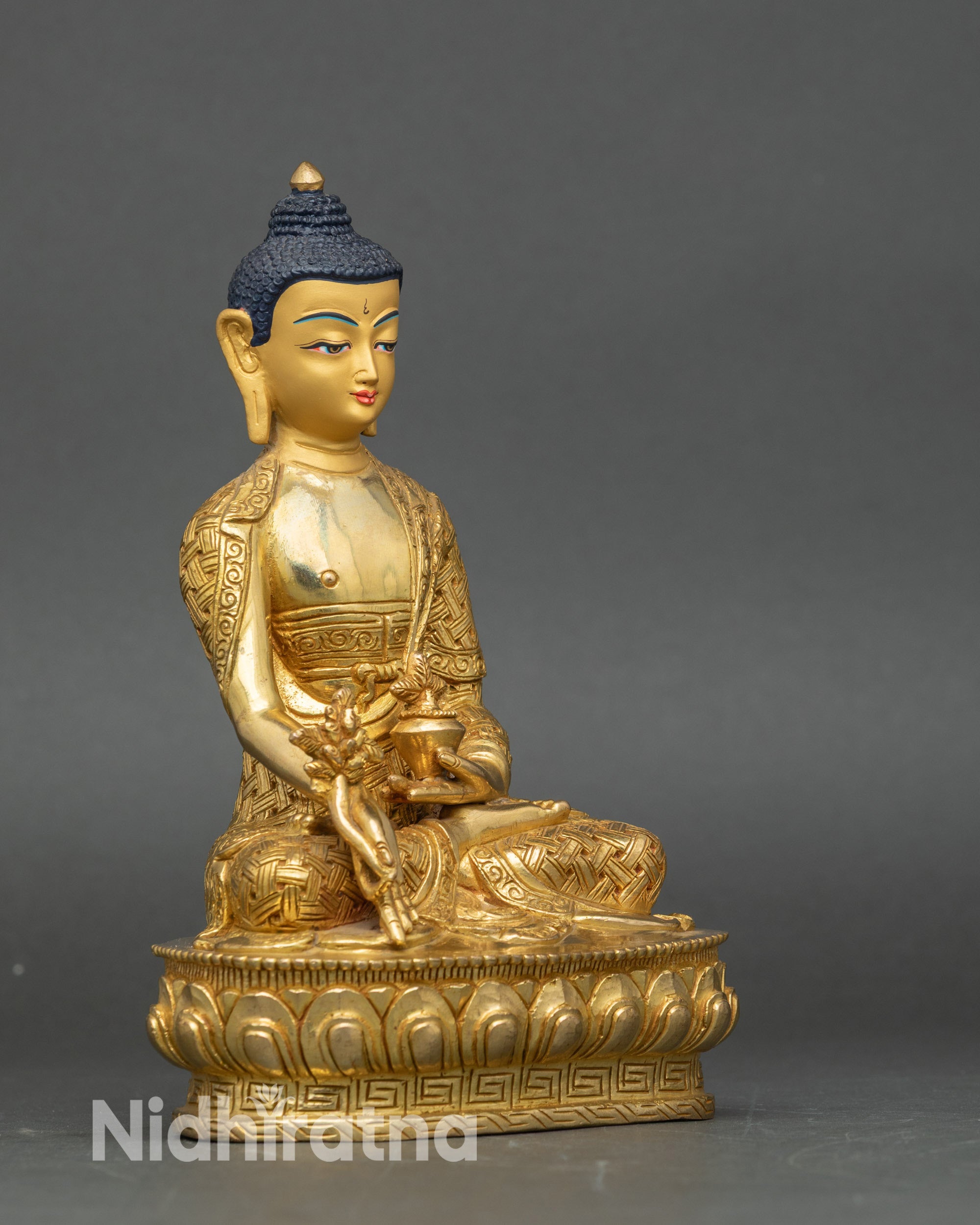 Right-side view of Medicine Buddha statue, seated on lotus, holding myrobalan vase and stem