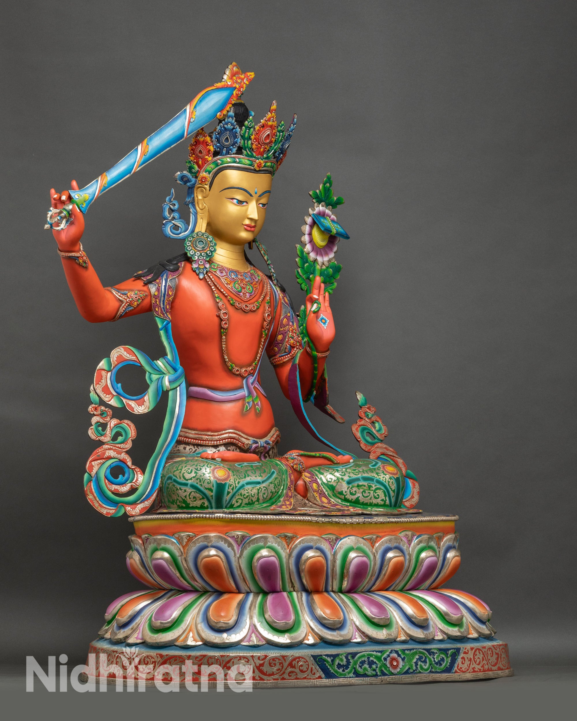 Right side profile of Manjushri statue seated on a colorful lotus base in Nepalese style