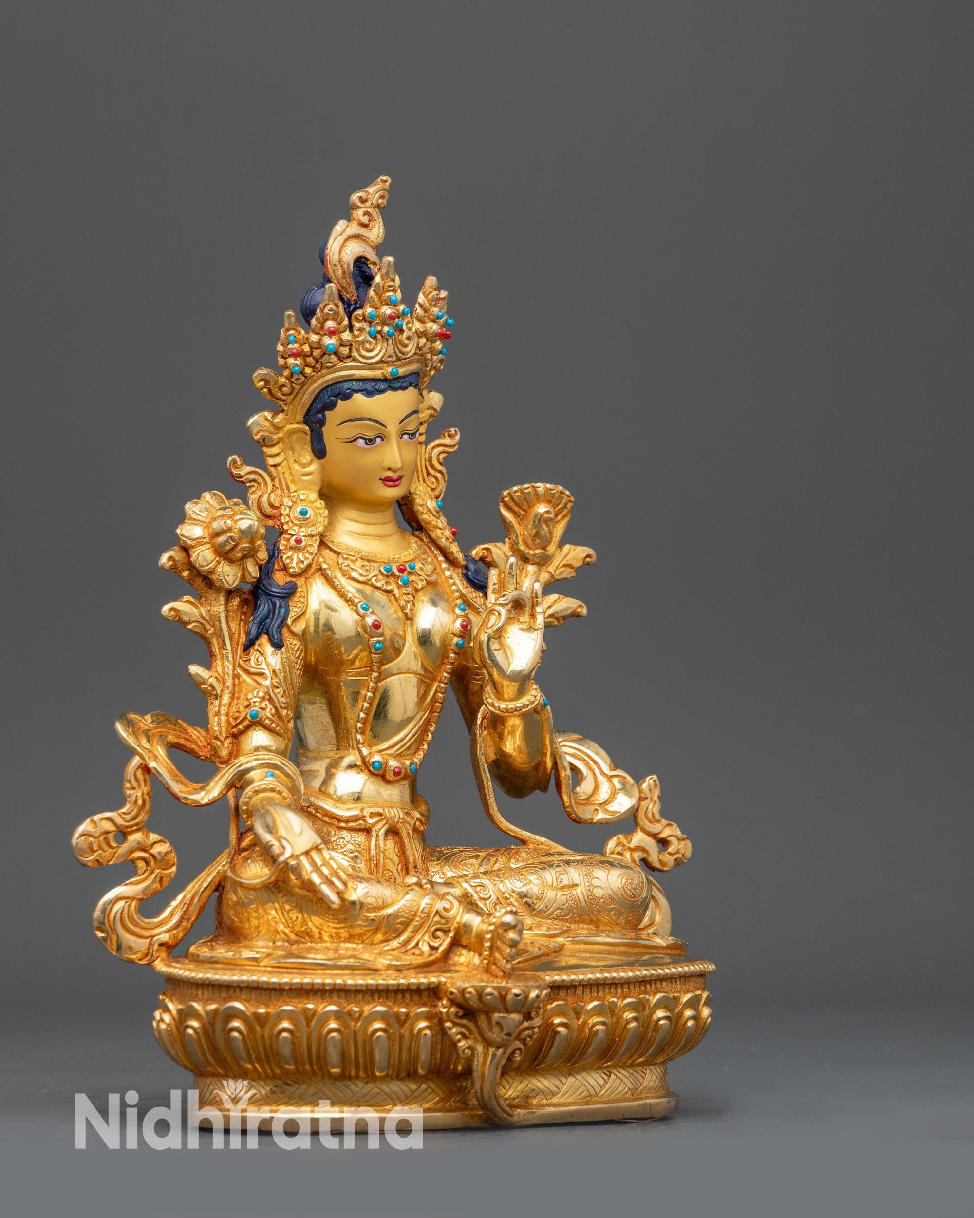Right view side Green Tara statue seated in royal ease on lotus throne
