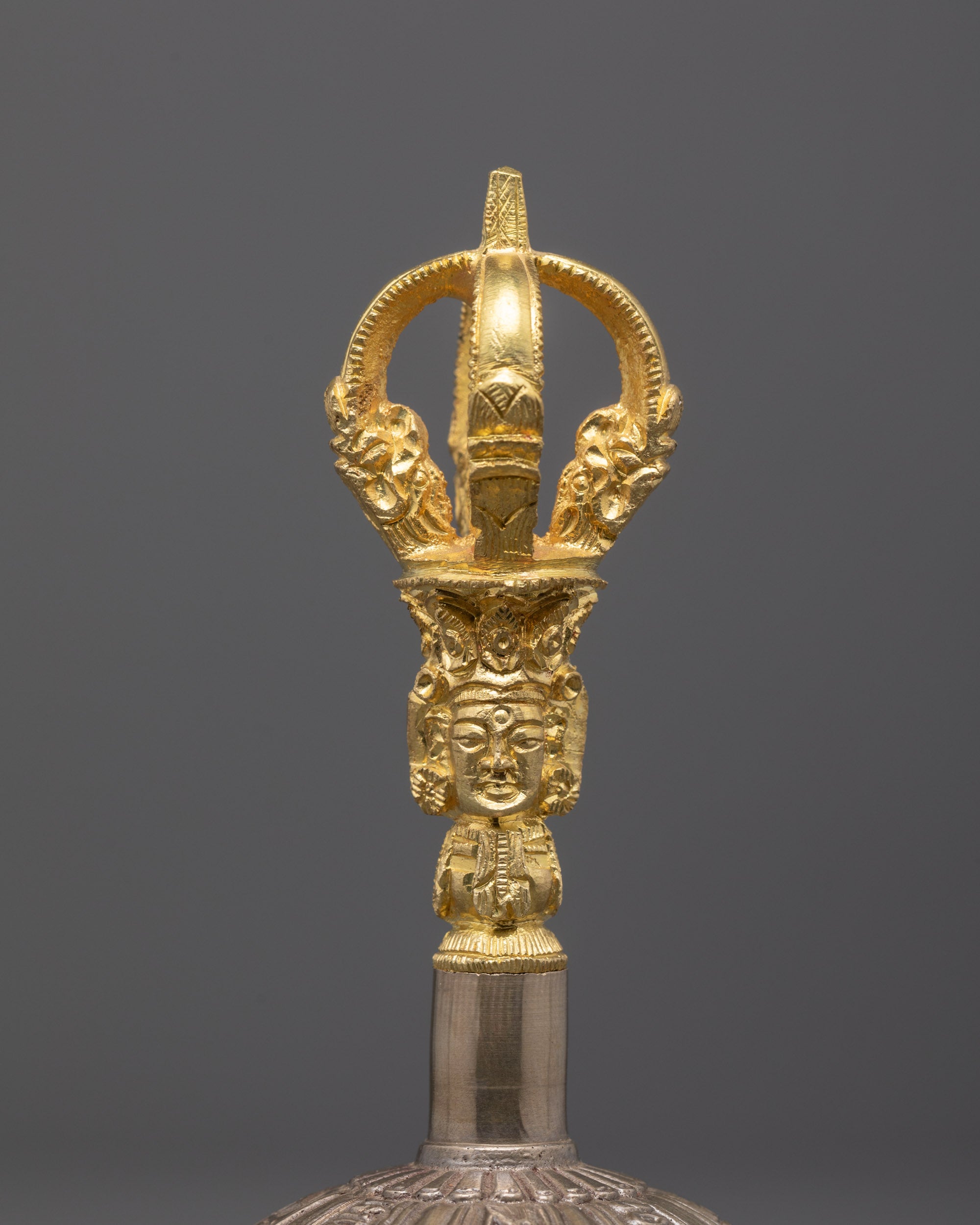 close up of vajra handle with carved patterns and sacred symbols in fine detail

