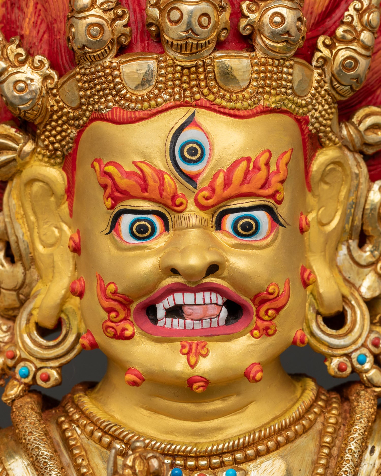 Sakya mahakala statue face close up revealing fierce expression, 24k gold painted face, crown of five skulls and divine wrathful energy