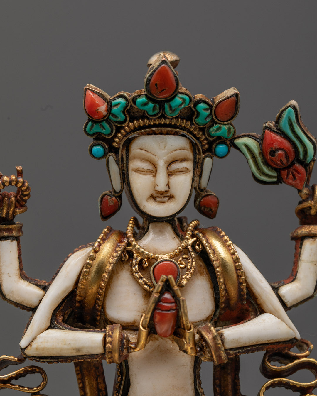 Serene face of Chenrezig Buddha statue with turquoise and coral inlays, radiating compassionate energy