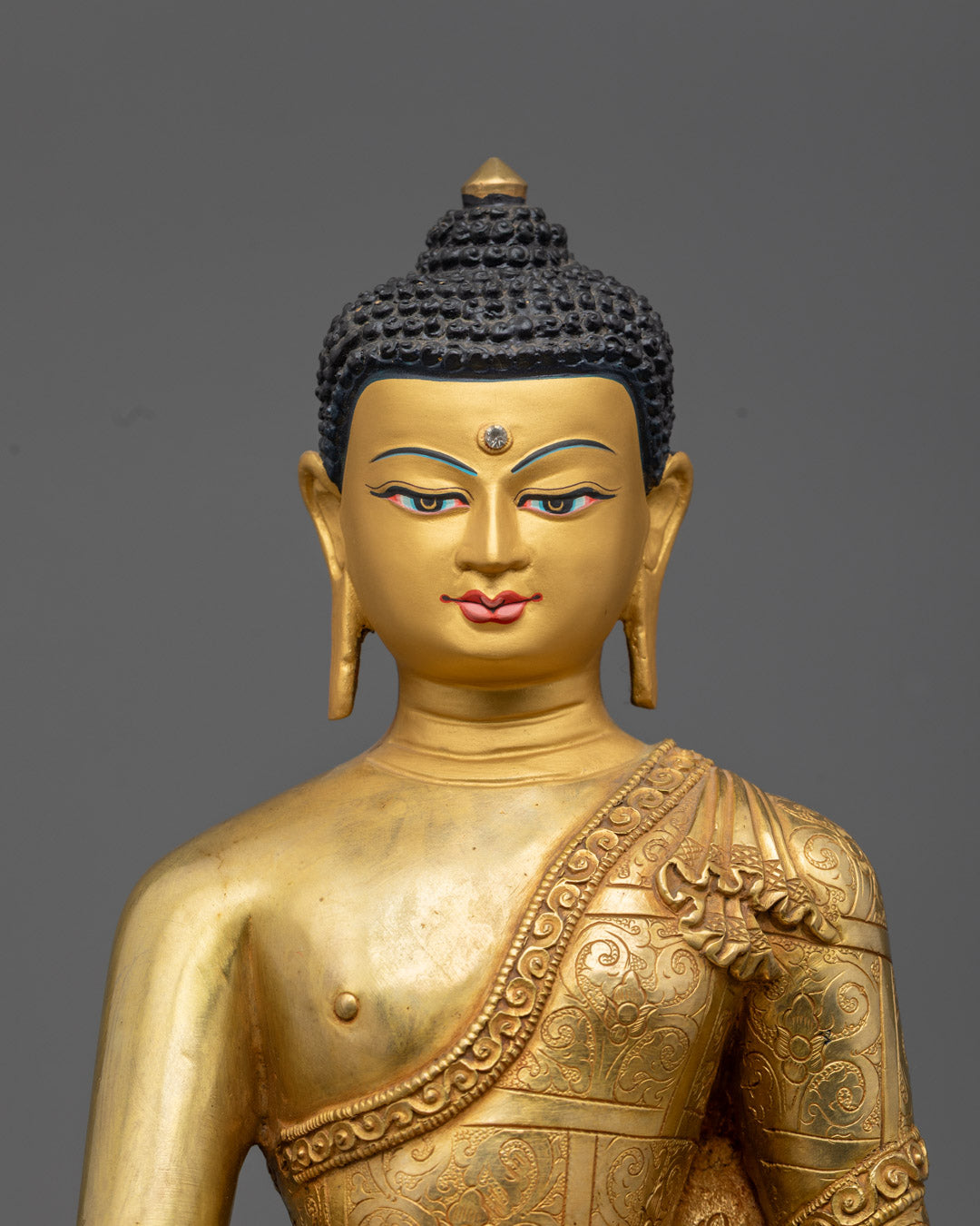Serene face of Shakyamuni Buddha statue with intricate gold fire gilding and turquoise-inlaid eyes, radiating enlightened wisdom