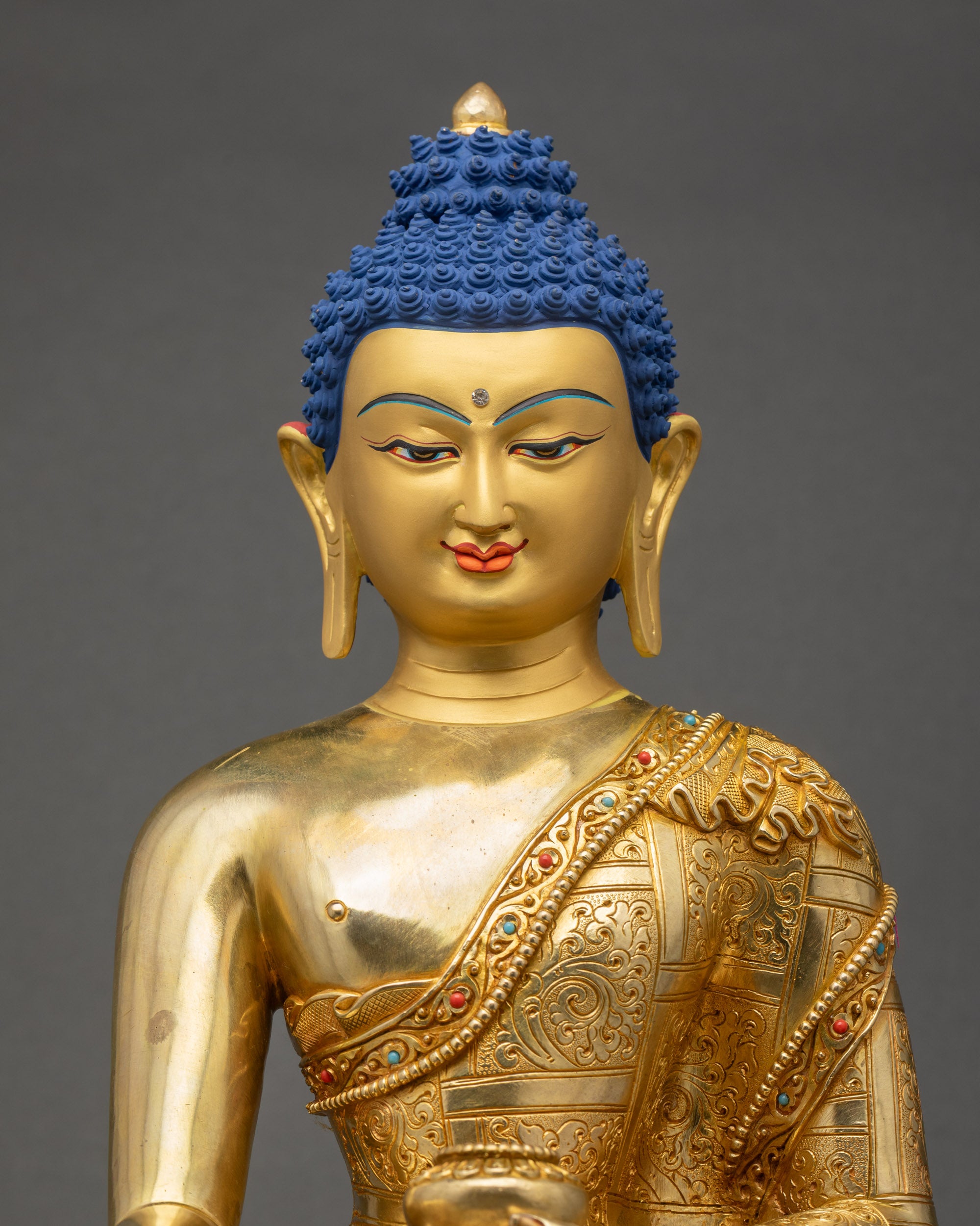 Close up of Lord Gautam Buddha statue showing serene 24K gold painted face