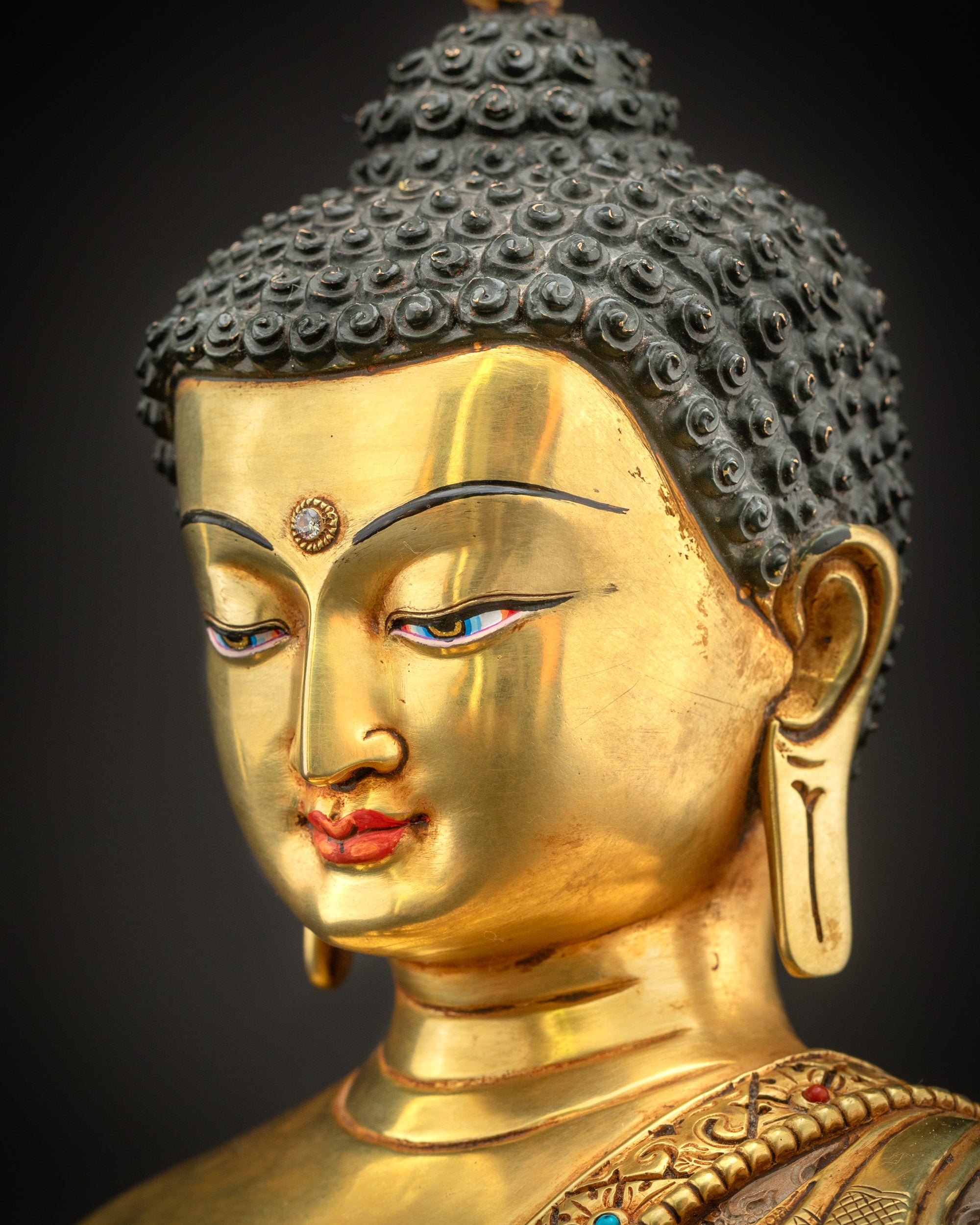 Side close up of Gautama Buddha face showing gentle features, elongated earlobes, and polished gold fire gilded finish.