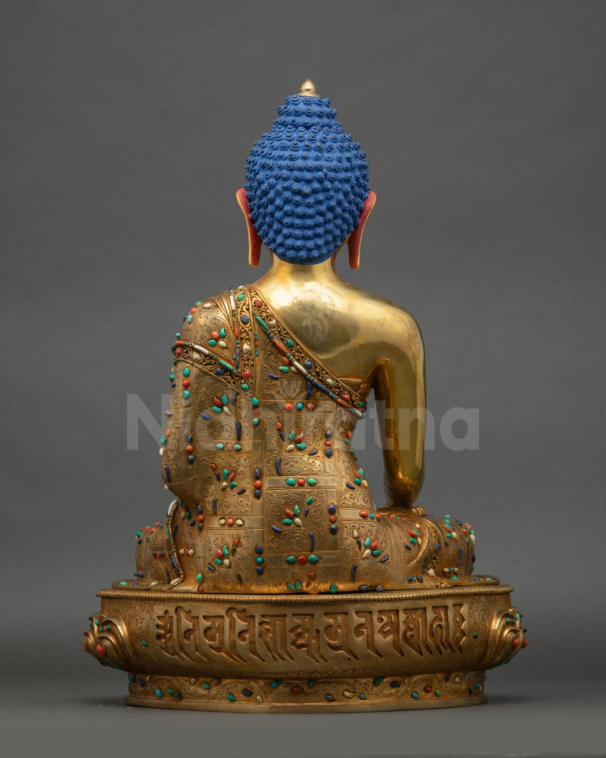 Back view of Shakyamuni Buddha statue showing detailed carvings on robe and posture