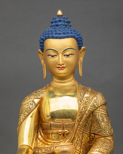 Shakyamuni Buddha statue close up with gold fire-gilded face and intricate robe