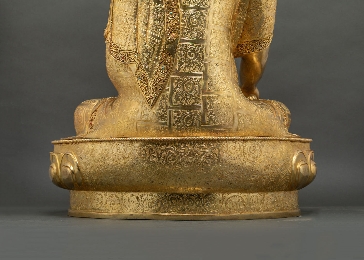 Side angle view of gold gilded Buddha statue on lotus pedestal base
