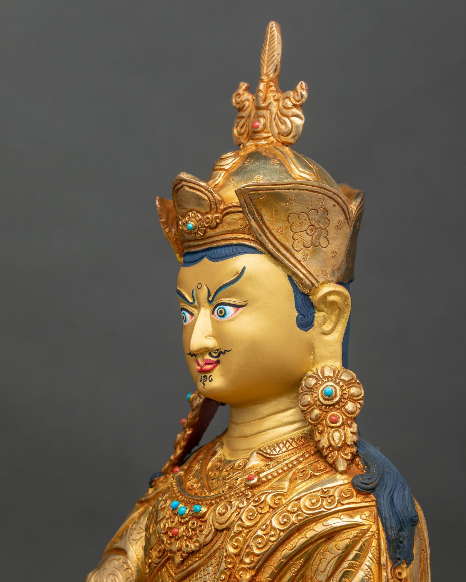 Side close-up of Guru Rinpoche statue, showing lotus seat and khatvanga staff