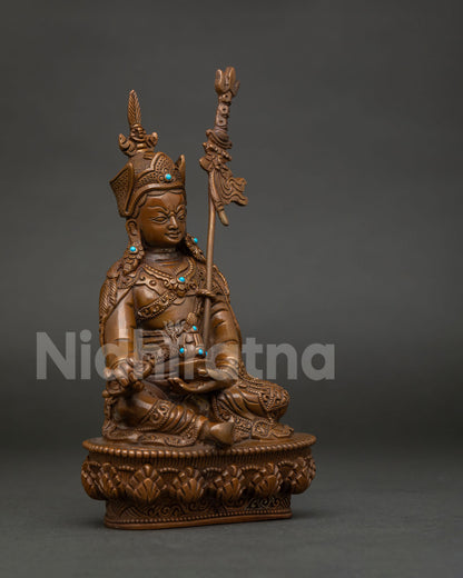 Side view of oxidized copper Guru Rinpoche statue with vajra skull cup and khatvanga staff.