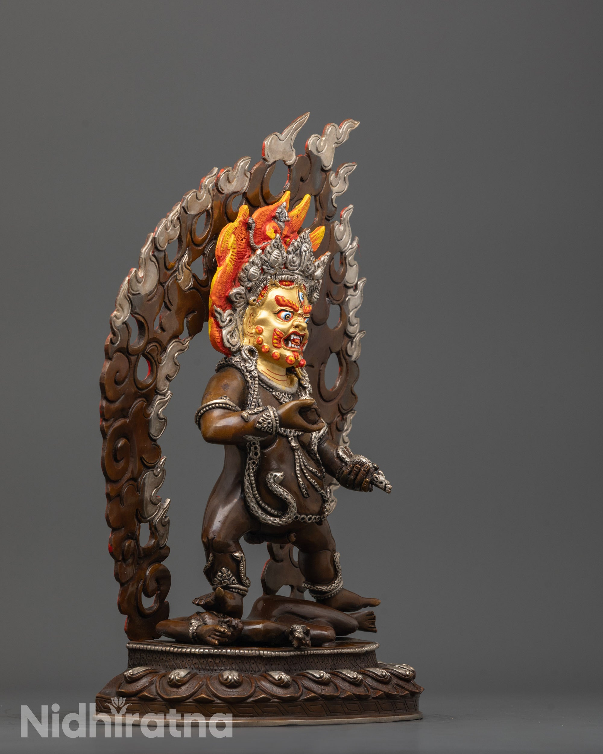 Side angle of Black Dzambhala Statue with oxidized copper body and silver-plated garments
