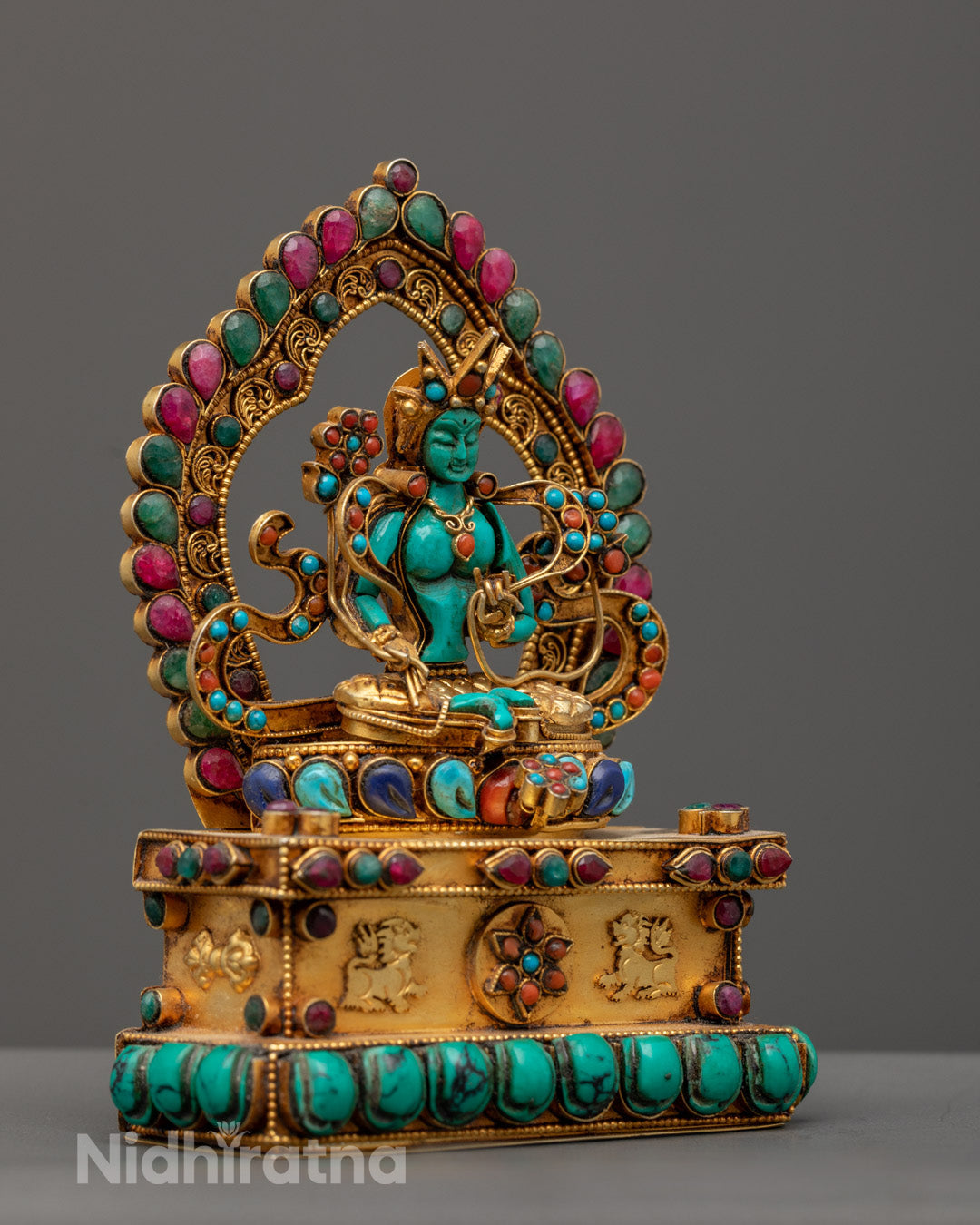 Green Tara sculpture showing detailed lotus petals and the mudras of refuge and blessings held by the goddess.