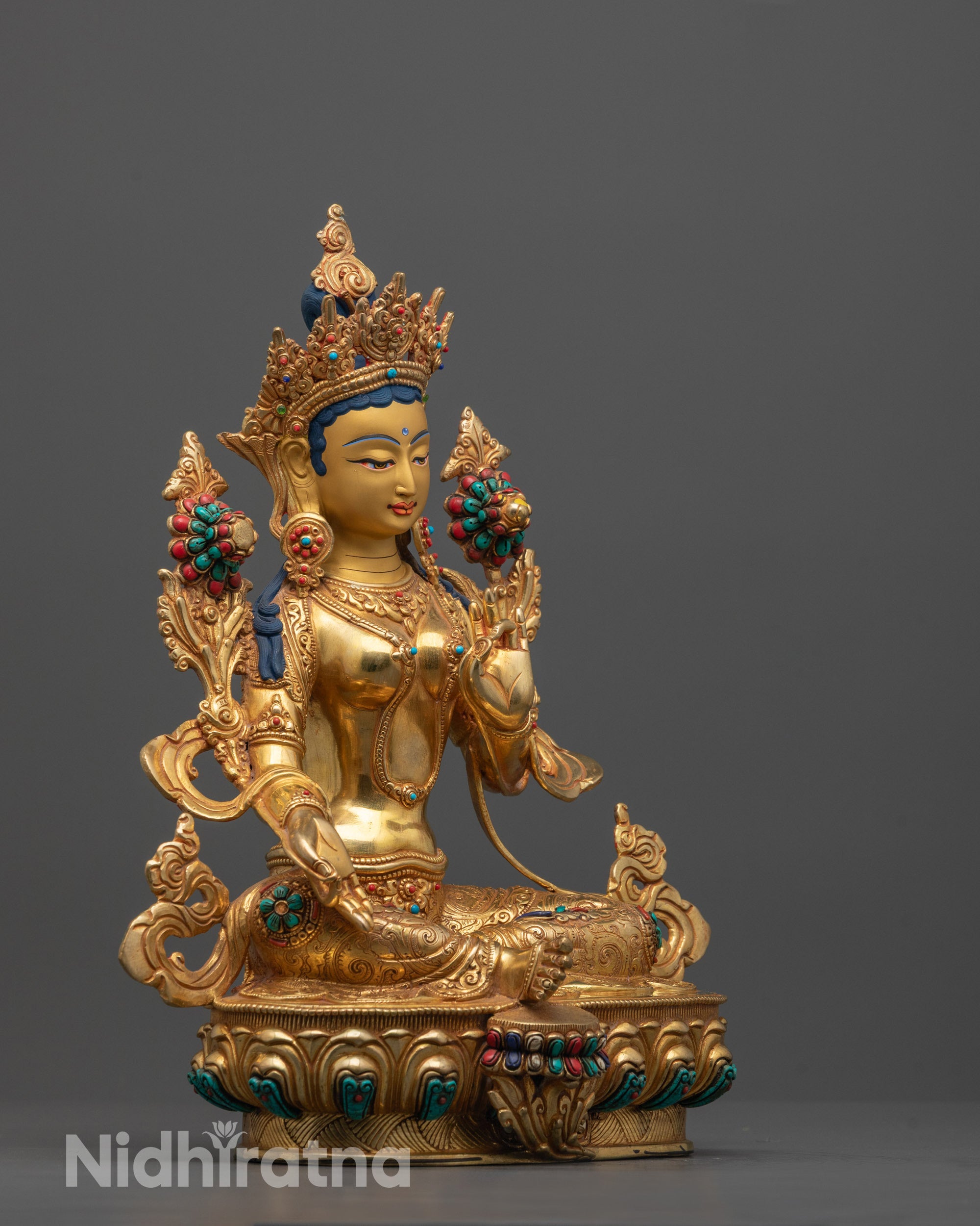 Side angle of Green Tara statue displaying her varada mudra hand gesture