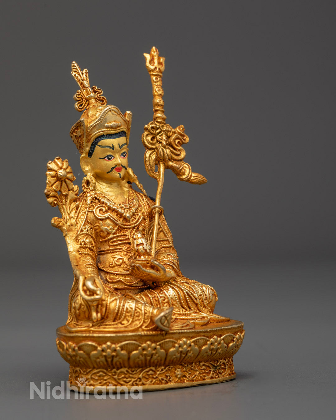 Side angle of Guru Menla statue showing Khaṭvāṅga trident and robe carvings