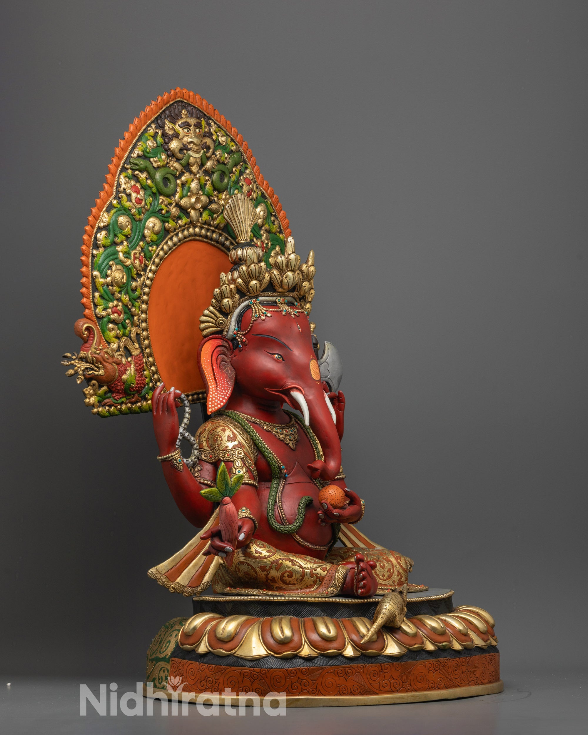 Side angle of Lord Ganesha statue with flowing robes and Mooshak near the lotus base