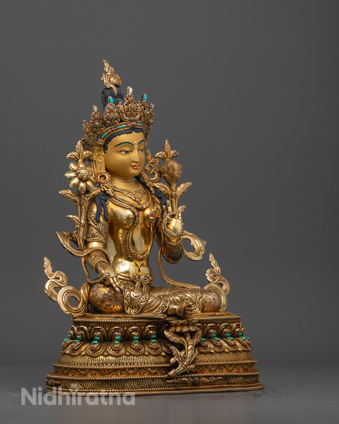 Side angle of Mother Tara statue showing fire-gilded body and detailed flowing robes, Buddhist deity
