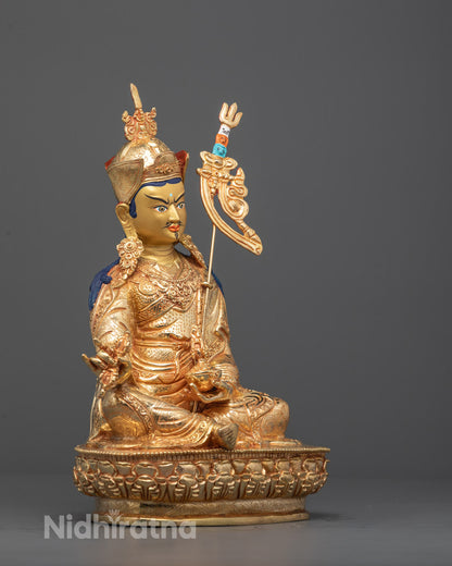 Side angle of Padmasambhava holding vajra, kapala vase, and trident in gold fire finish