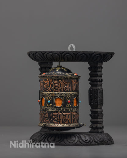 Side angle of Tibetan mantra prayer wheel on carved dark wood frame