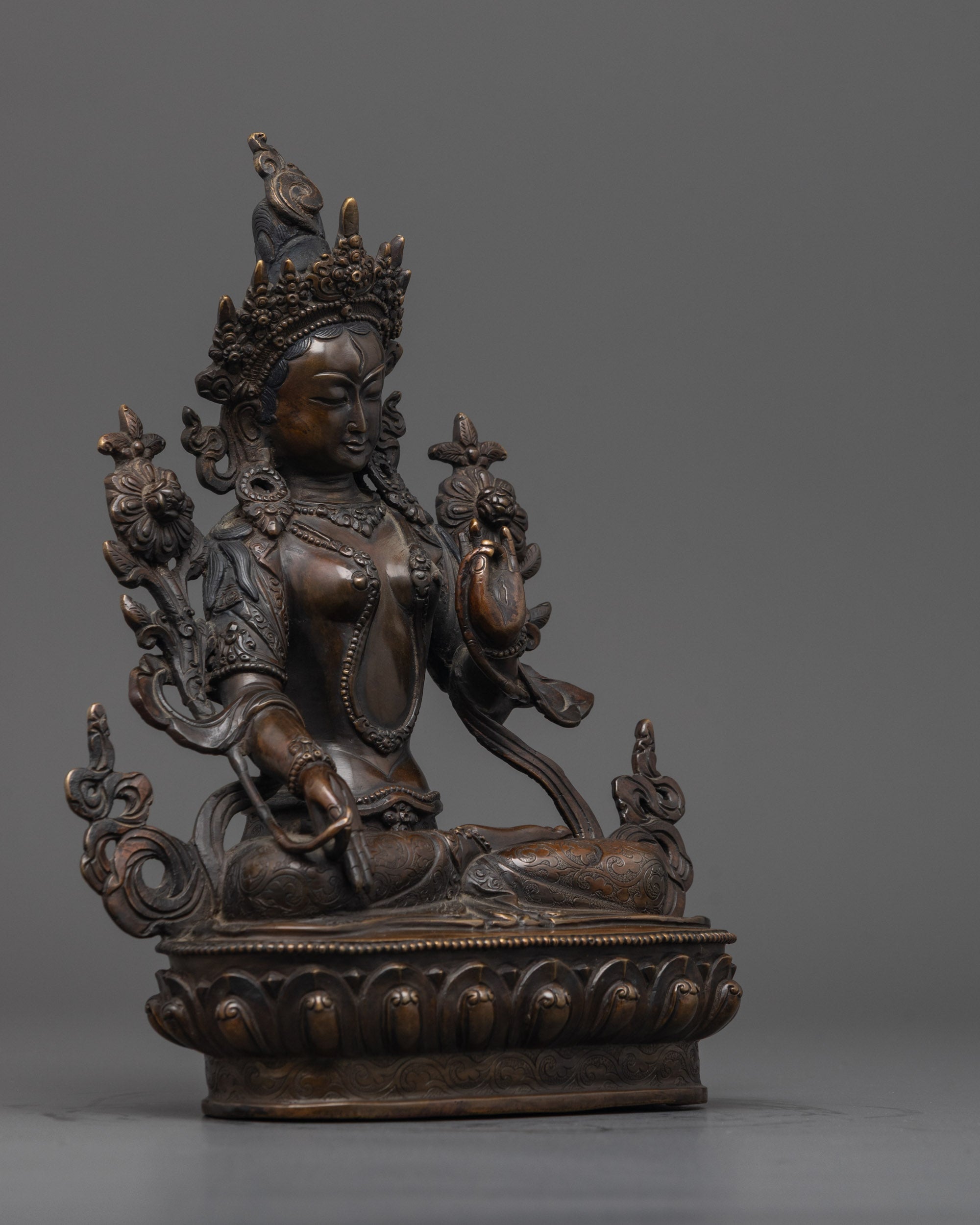 Side angle of White Tara sculpture showing intricate lotus throne