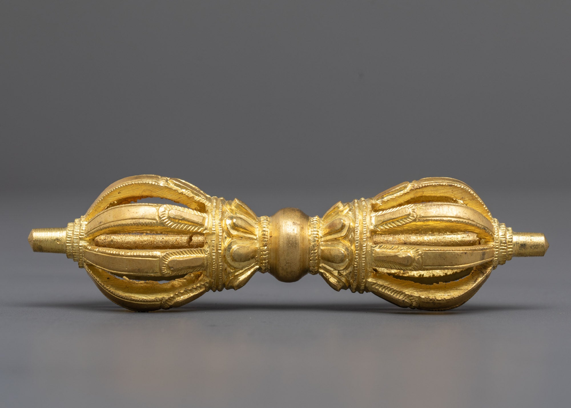 Side angle of copper dorje with intricate gold-plated spiritual design and texture