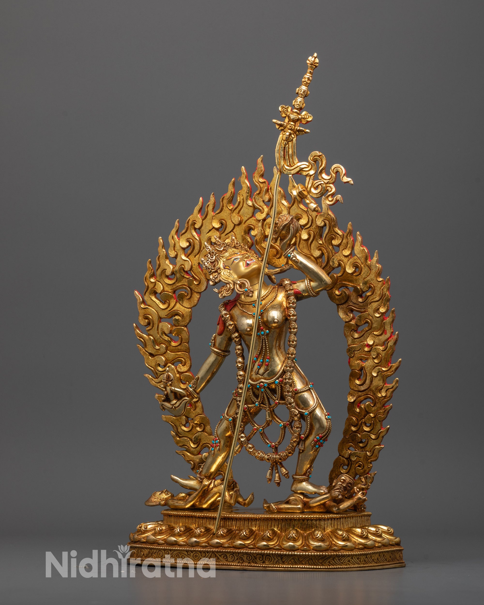 Side angle of fire-gilded Vajrayogini statue showing trident and sacred carvings