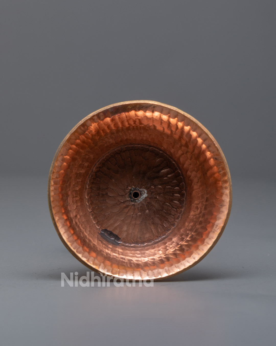 Side angle of handcrafted Himalayan butter lamp with flame lit