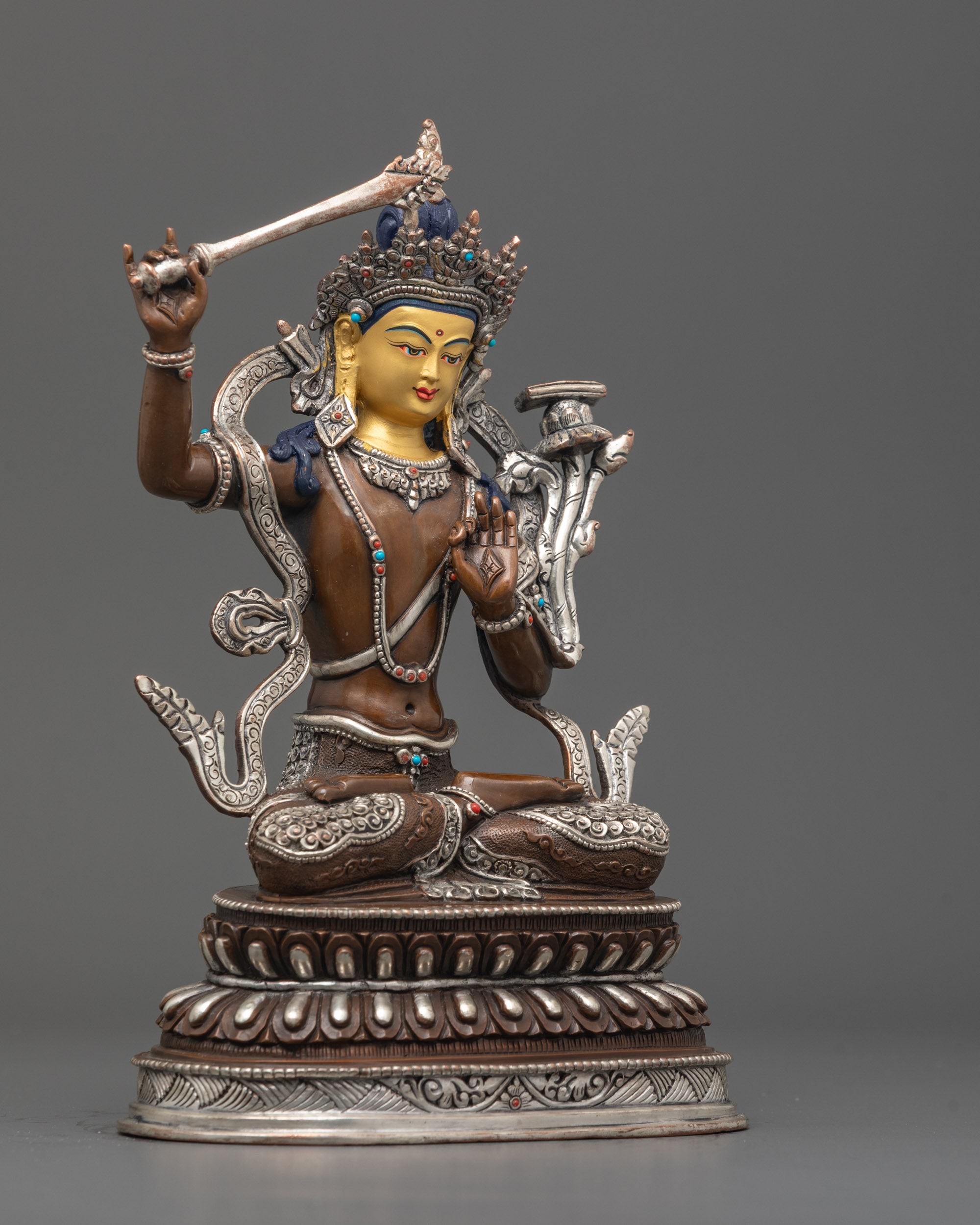 Side angle of handcrafted Manjushri statue showing silver-plated robe and lotus throne