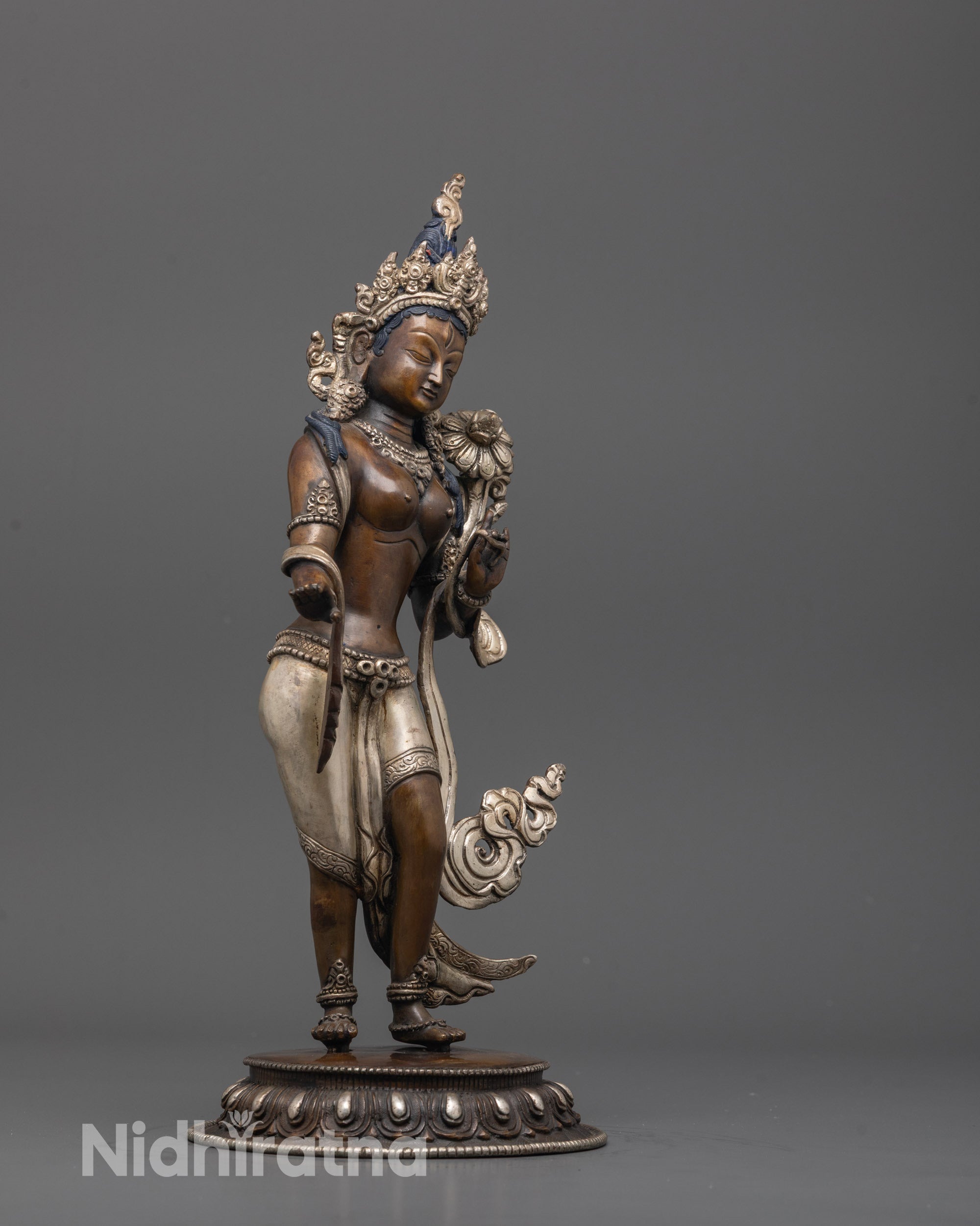 Side angle of handcrafted Standing Green Tara statue holding utpala flowers in meditation pose
