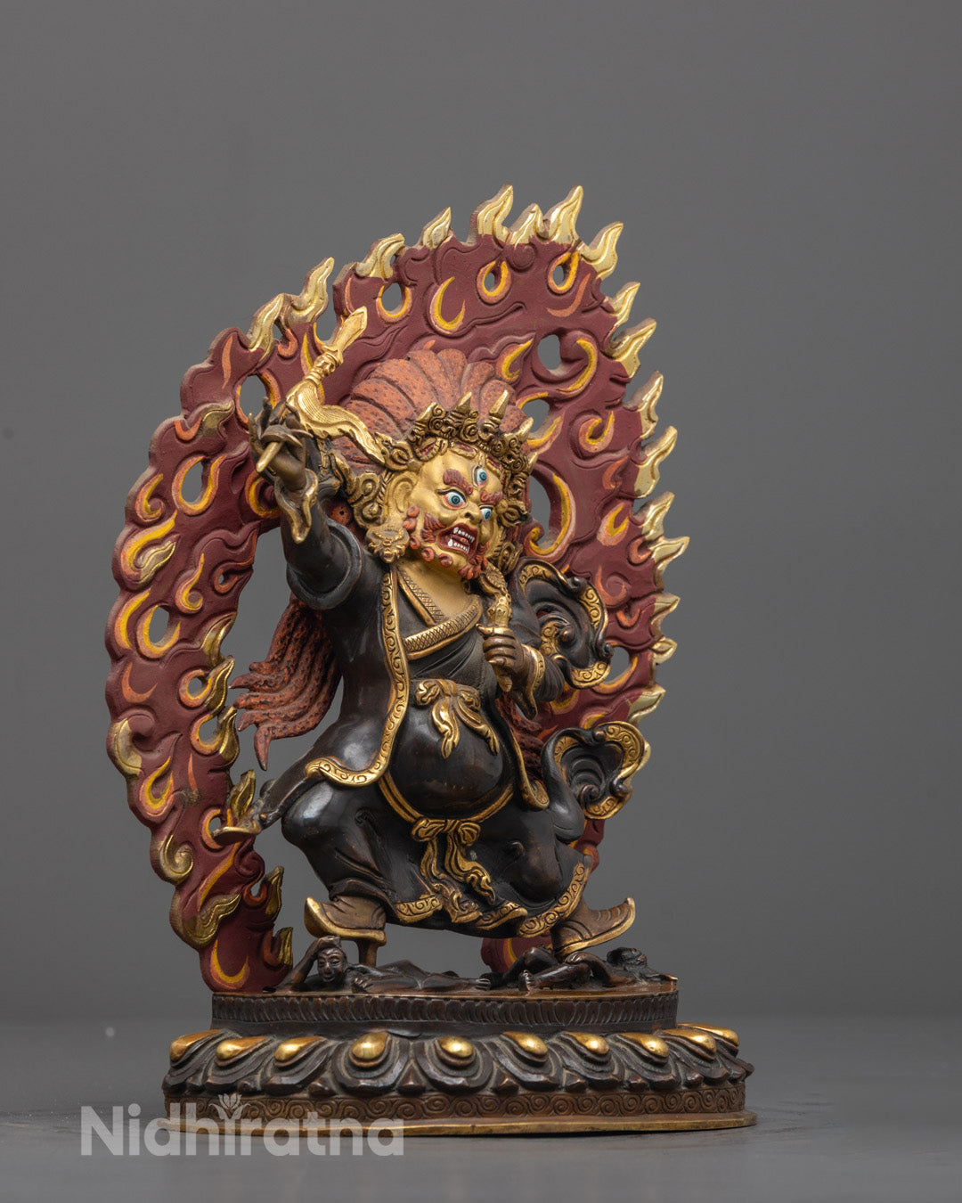 Side angle of oxidized copper Mahakala sculpture standing on lotus seat with detailed gold accents