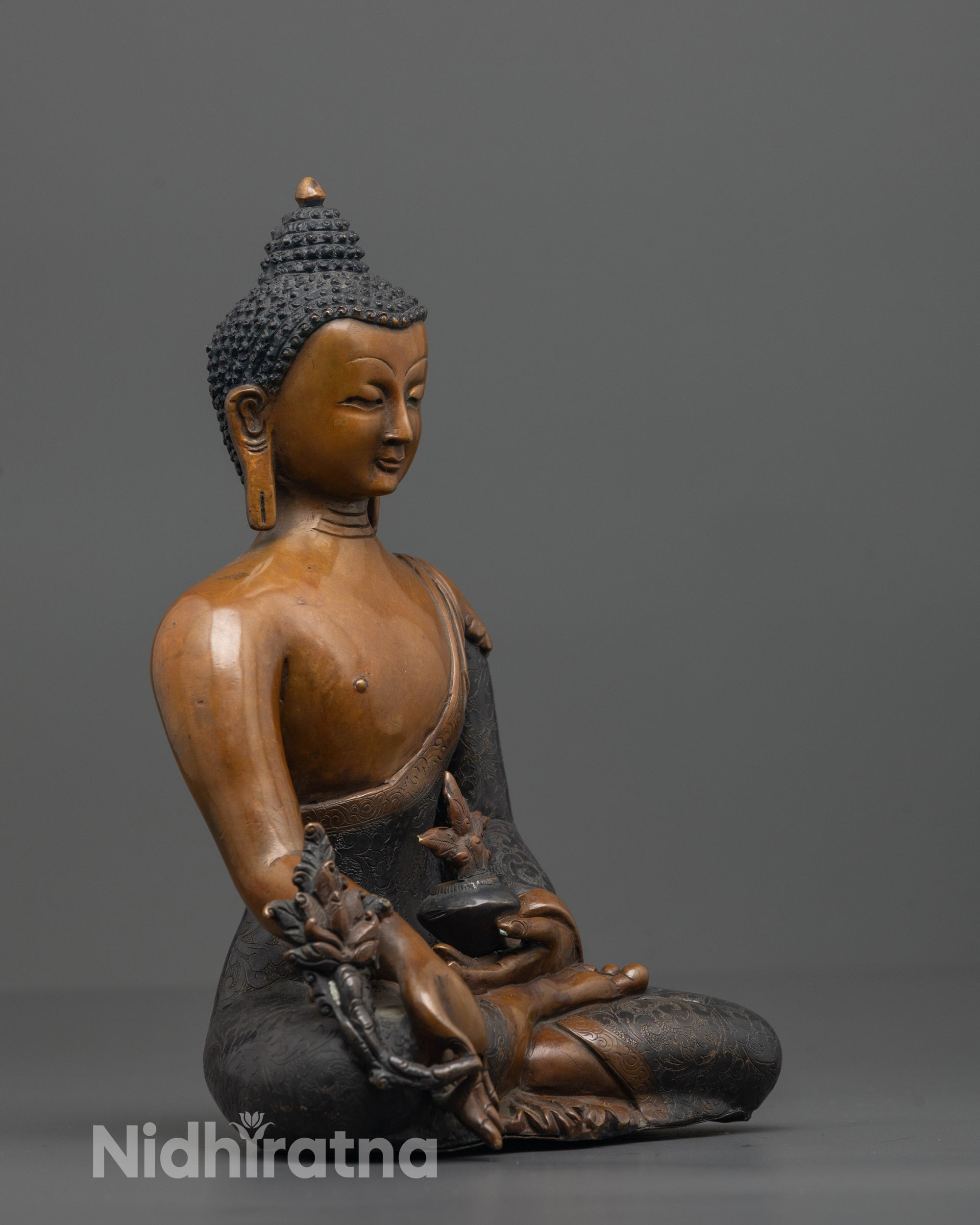 Side angle showing carved patterns on monk’s robe of Medicine Buddha statue
