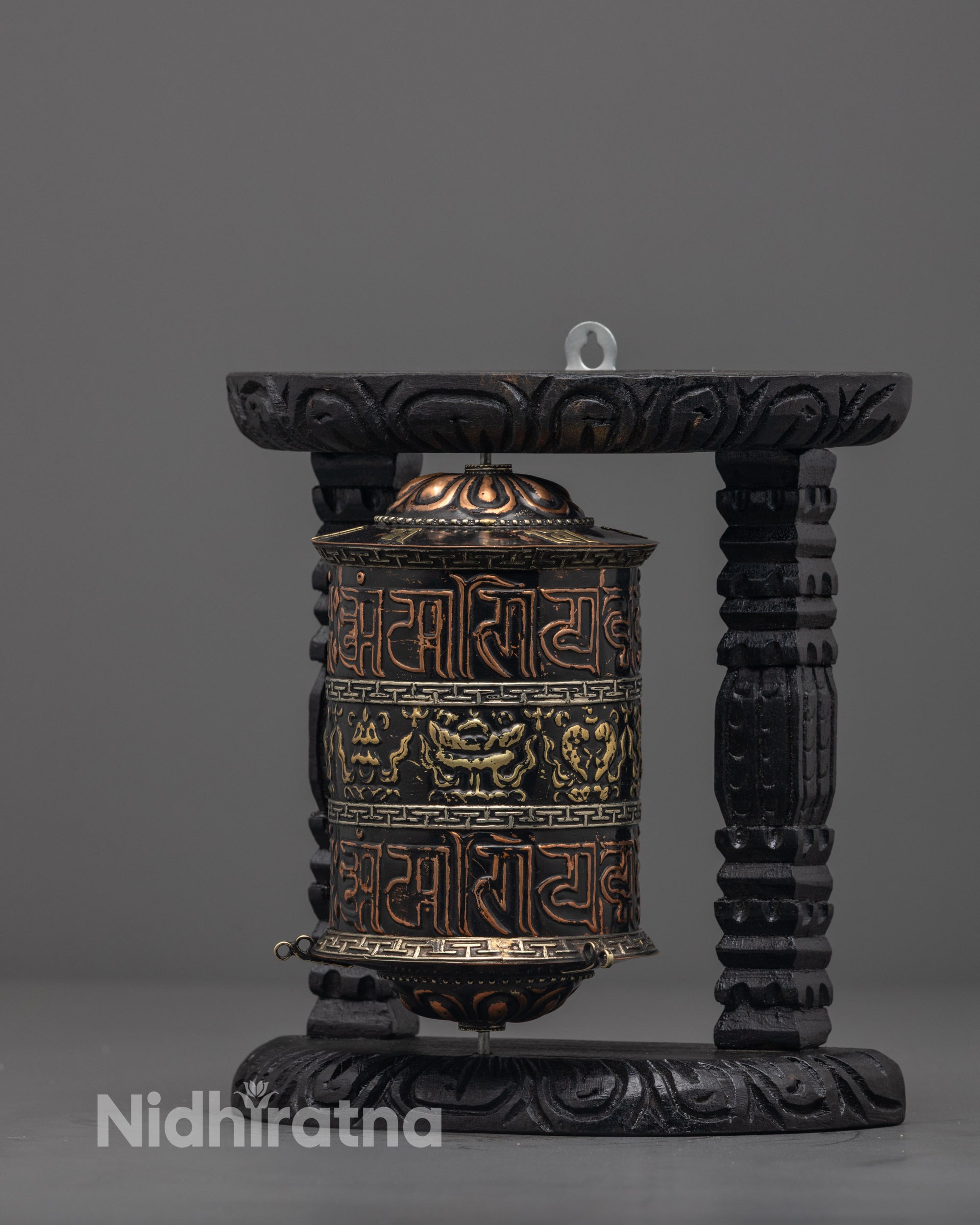 Side angle showing intricately carved dark wood frame of Buddhist mantra spinner