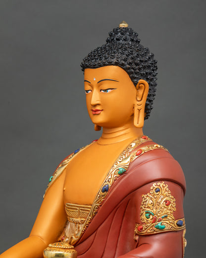 Side close-up of Buddha sculpture highlighting semi-precious stones and gold fire-gilded monk’s garment