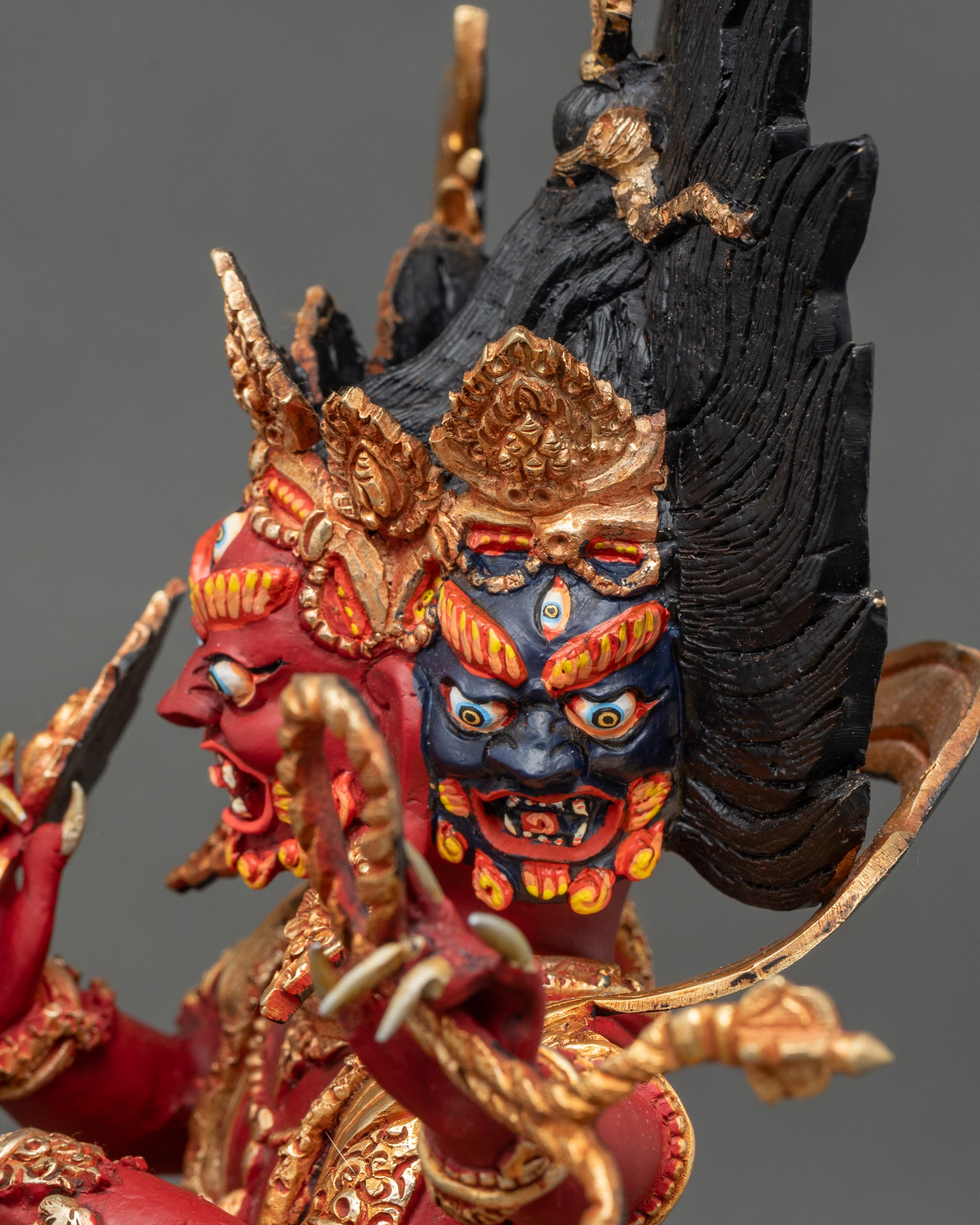 Side close-up of Red Dzambhala statue, six arms and lotus seat with subjugated figures