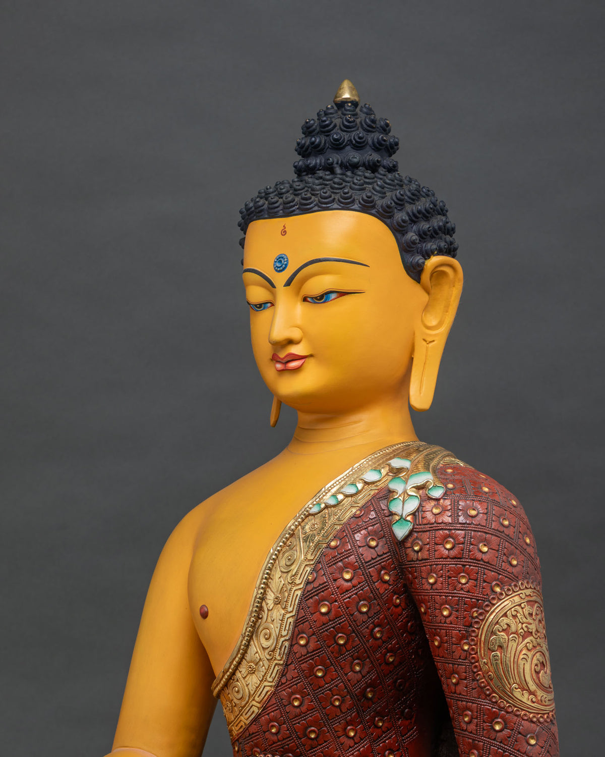 Side close-up of colorful Buddha statue, painted robe and gold-gilded robe