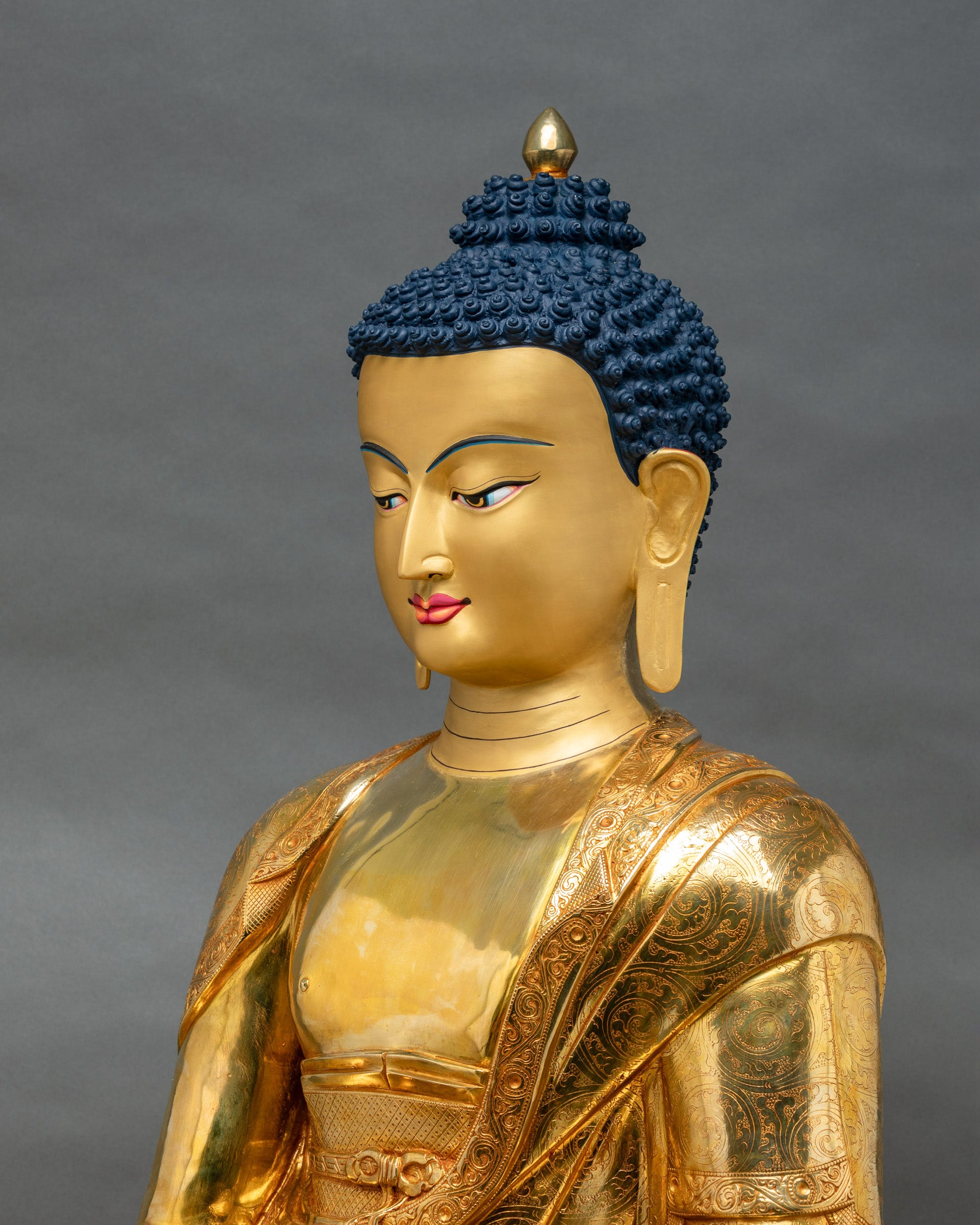 Side close-up of copper Shakyamuni Buddha showing layered robe carvings and gilded lotus petal throne