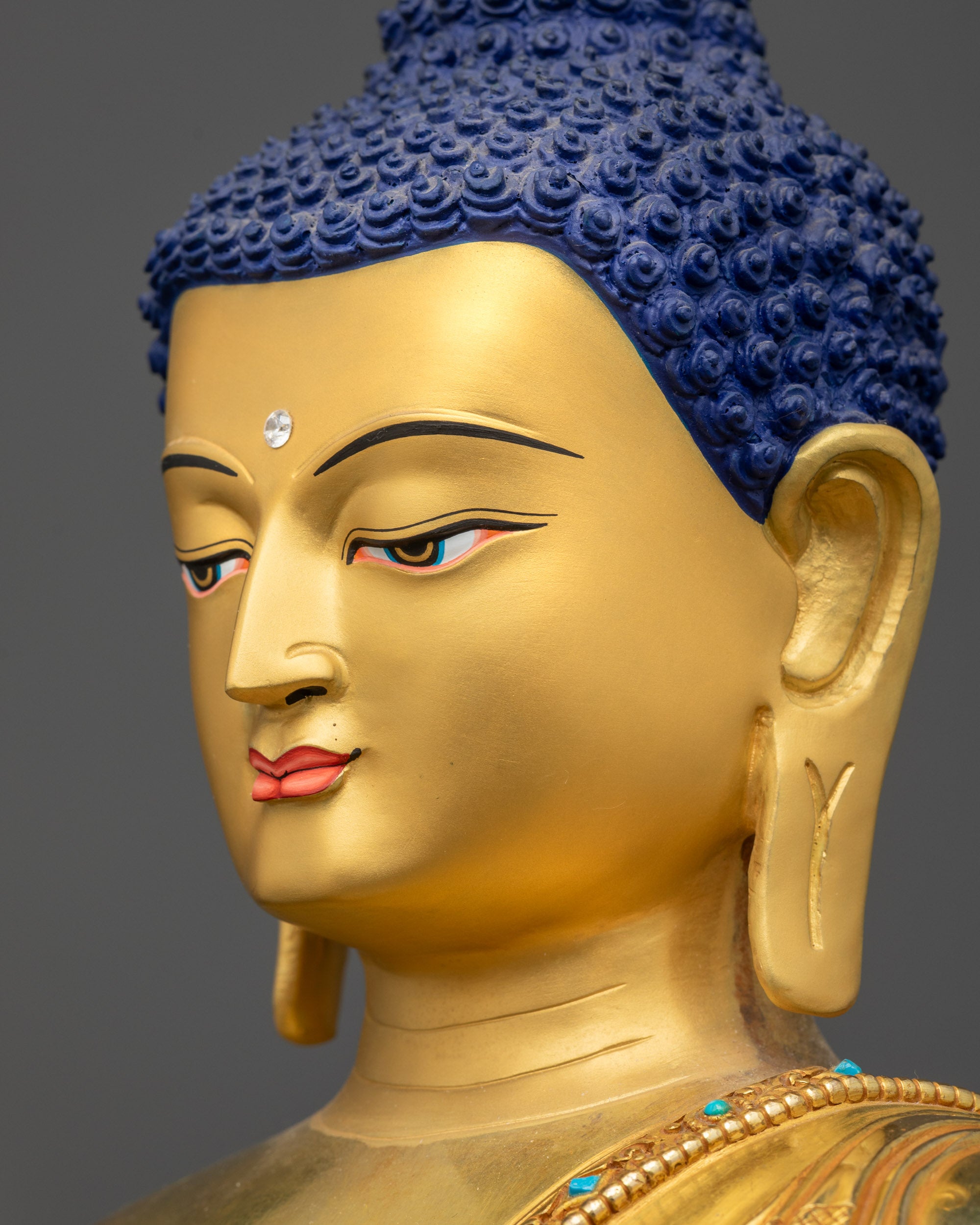 Side close up face of Amoghasiddhi Buddha statue with semi-precious stone-adorned robe