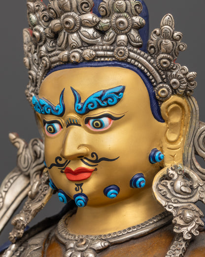 Side close up face of Dzambhala statue highlighting gold-gilded expression and ornate crown
