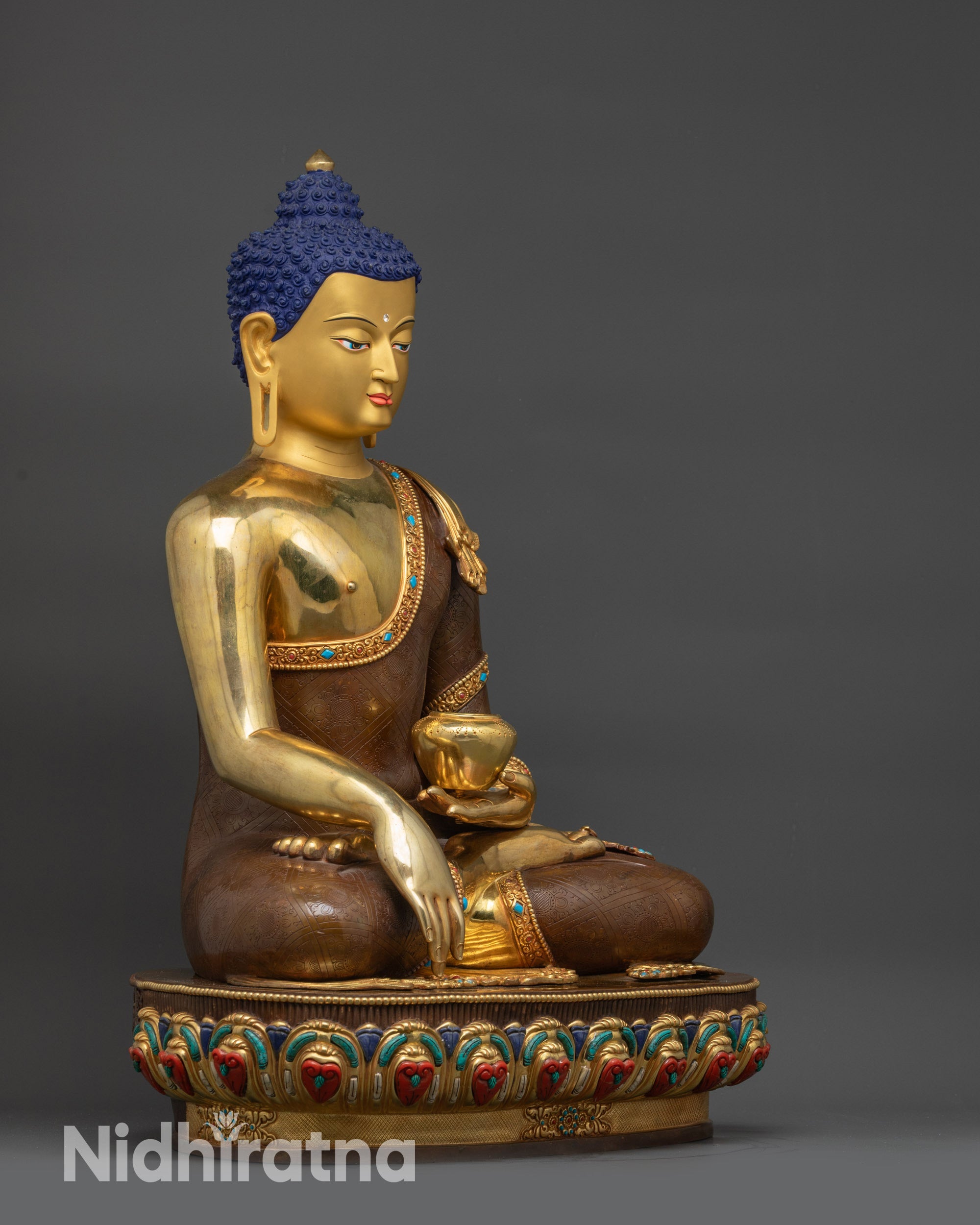 Side close up of Gautama Buddha showing begging bowl and carved robe details
