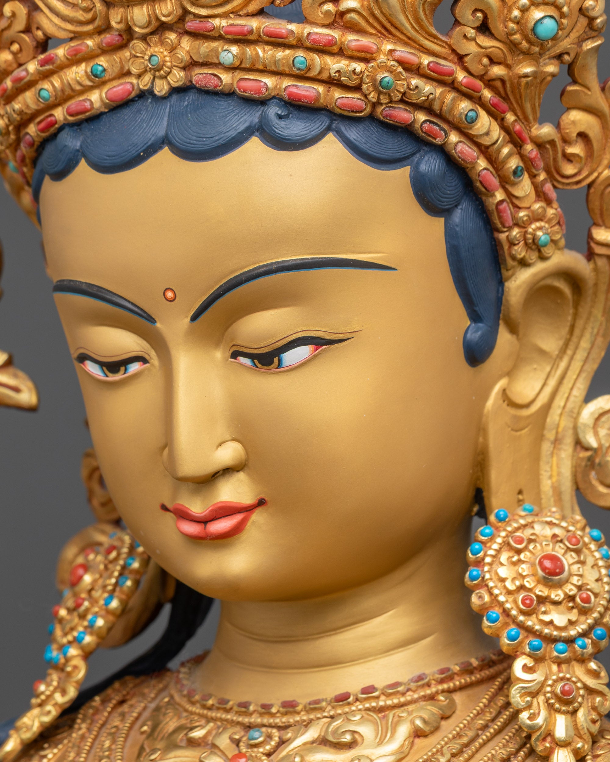 Side close up of Green Tara Statue face with tranquil gold-gilded features