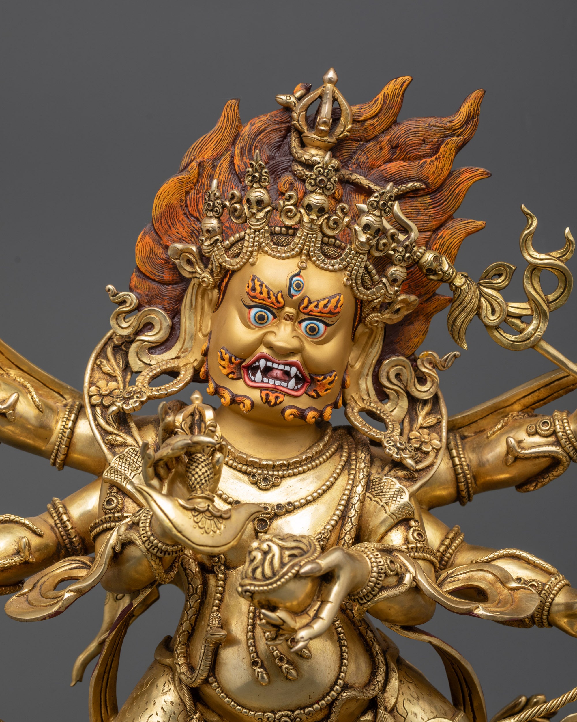 Side close up of Mahakala statue showing six arms and swirling robes