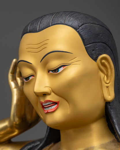 Side close up of Milarepa gold-gilded face holding kapala in classic listening posture
