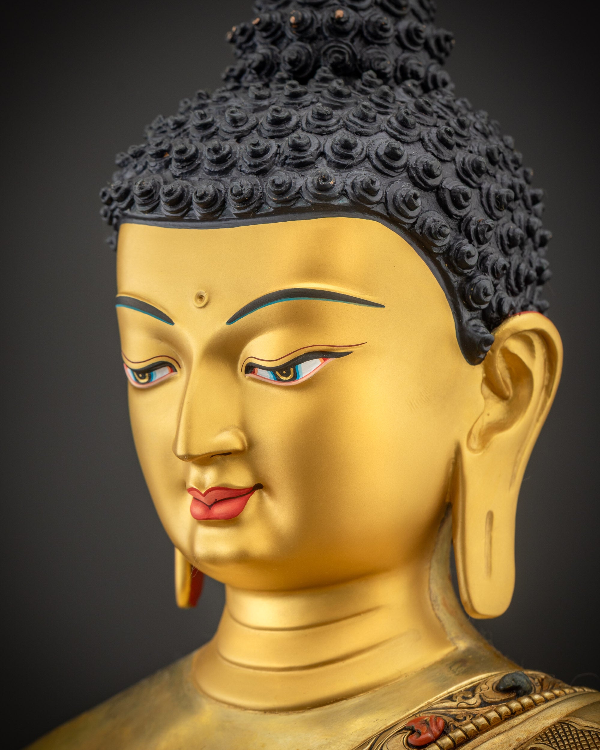 Side close up of Shakyamuni Buddha face showing gold gilded features and soft details
