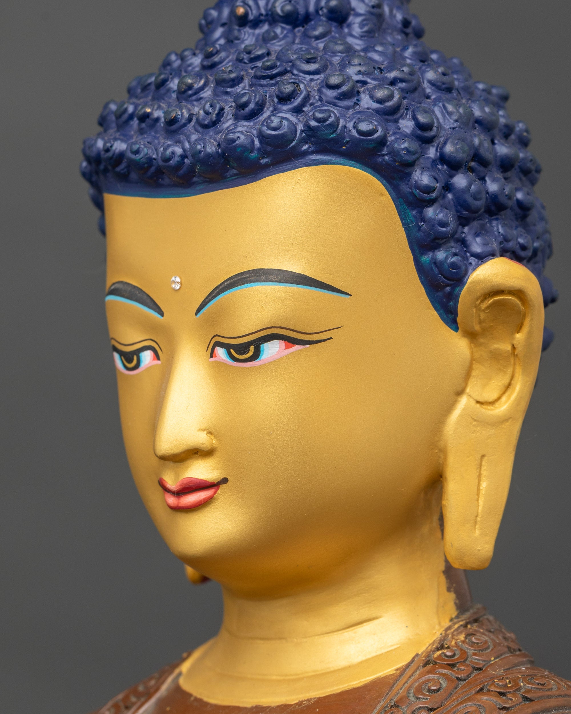 Side detail of Buddha statue in oxidized copper showing intricate lotus robe engravings