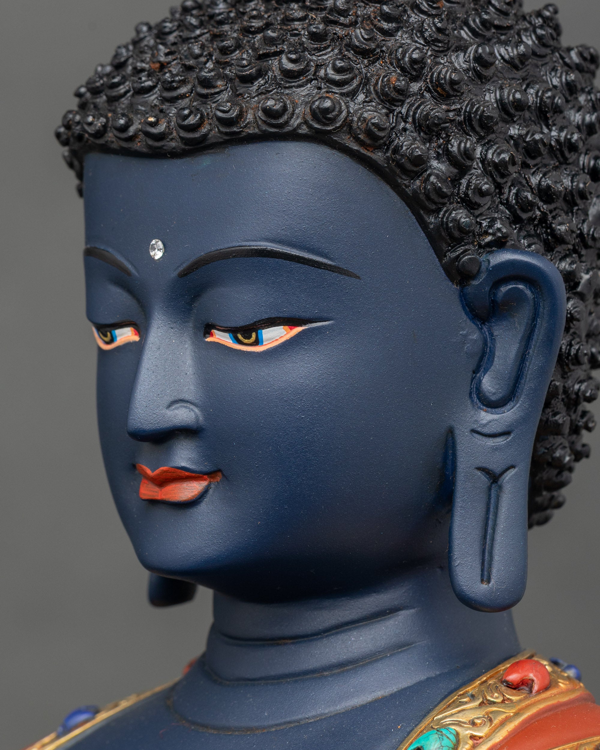 Side face close-up of Bhaisajyaguru statue, detailed gold fire-gilded features and serene expression