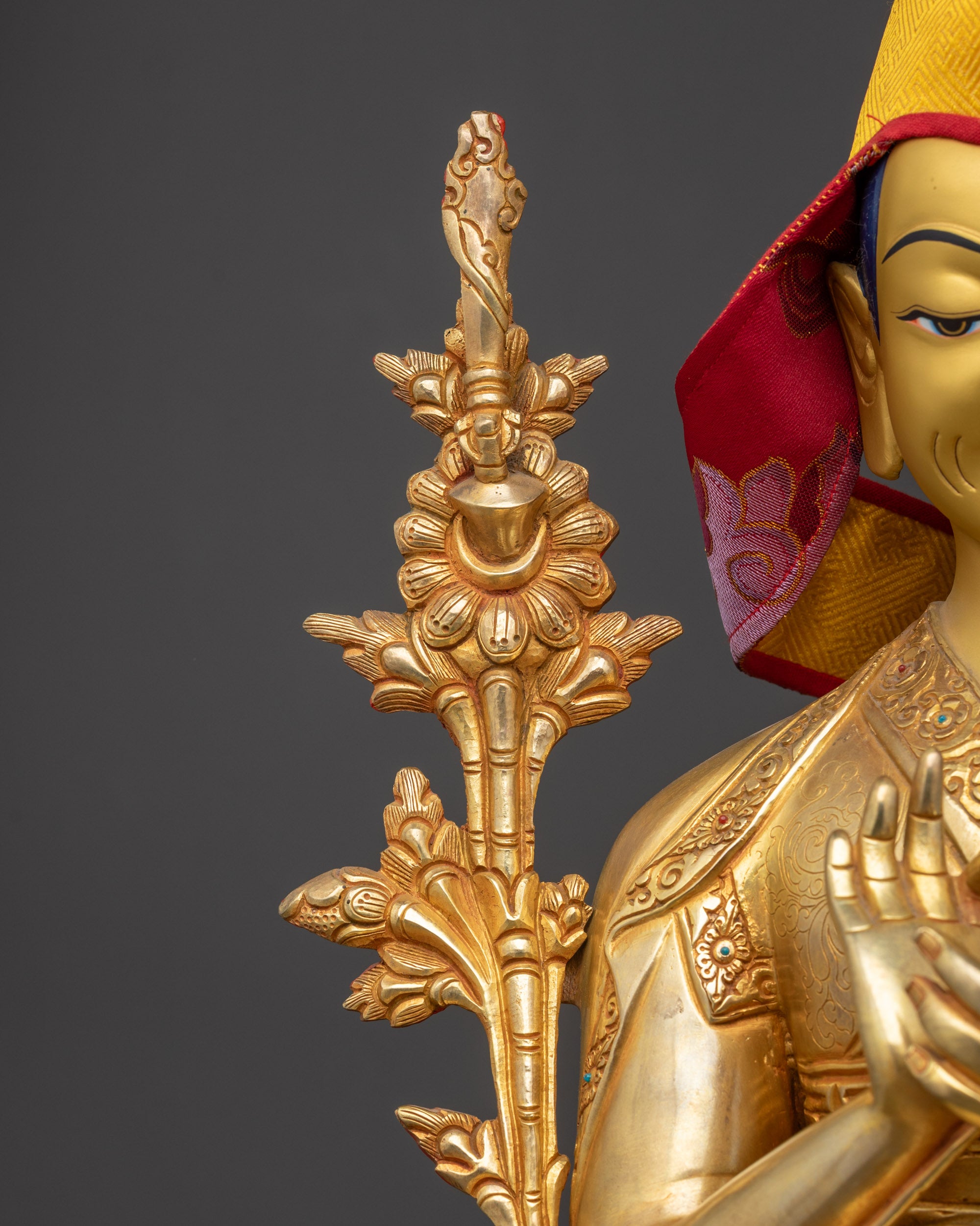 Side profile of Gyaltsab Je holding a scripture in Vitarka Mudra, yellow Pandita hat, and monastic robes.