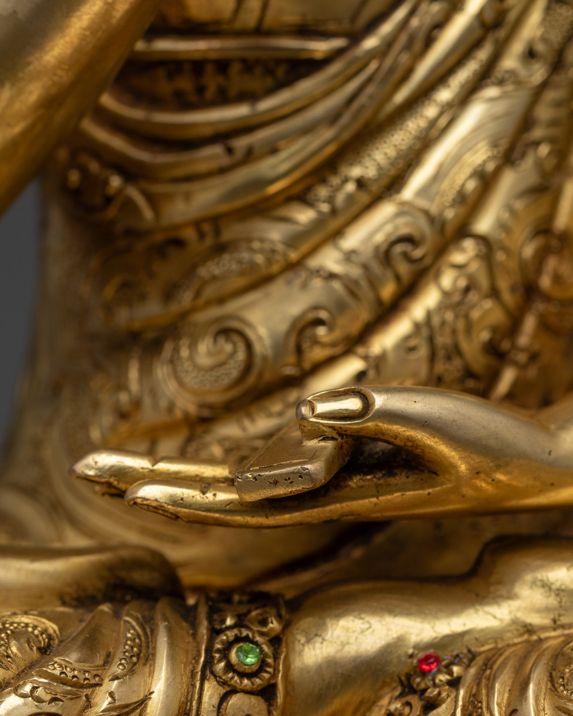 Side profile of Gyaltsab Je statue in vitarka mudra with ornate robes and copper base