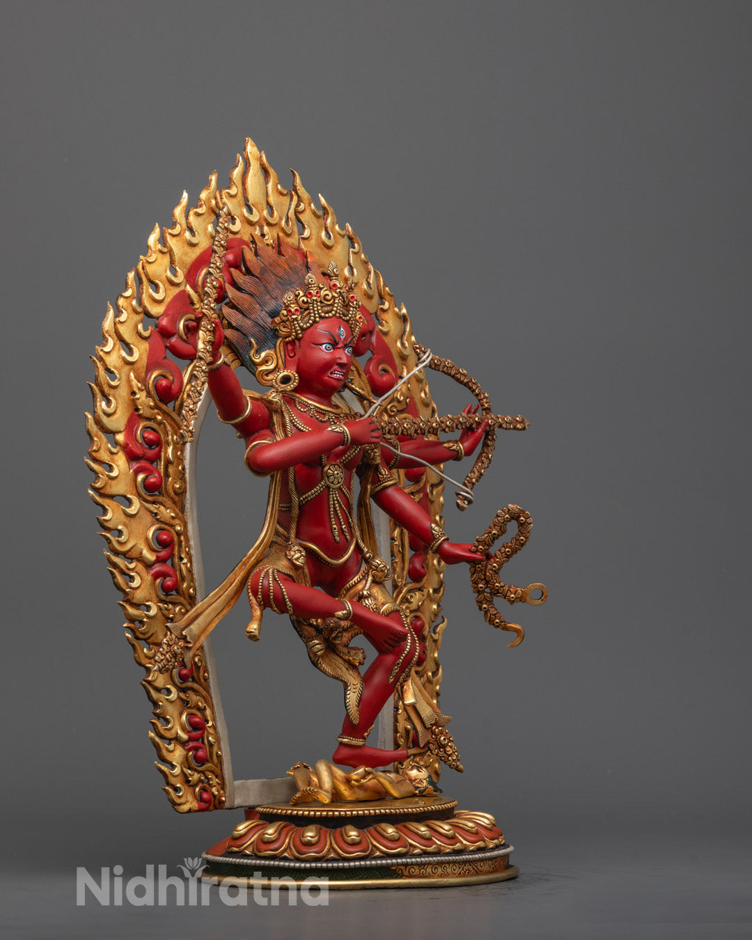 Side profile of red Kurukulla deity holding bow and arrow, showing intricate jewelry